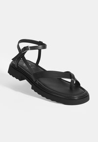 Zwarte sandaal met een platte rubberen zool, kruislingse leren banden en een verstelbare enkelgesp. Gladde textuur met minimale afwerking.