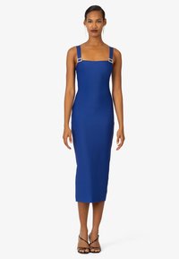 Robe midi ajustée bleue avec encolure carrée, larges bretelles et accents en métal rectangulaires. Texture lisse, couleur unie, sans motifs.