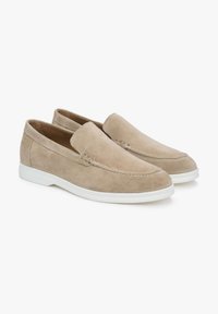 Beige suede slip-on shoes with a smooth texture, featuring white rubber soles and subtle stitched detailing along the upper.