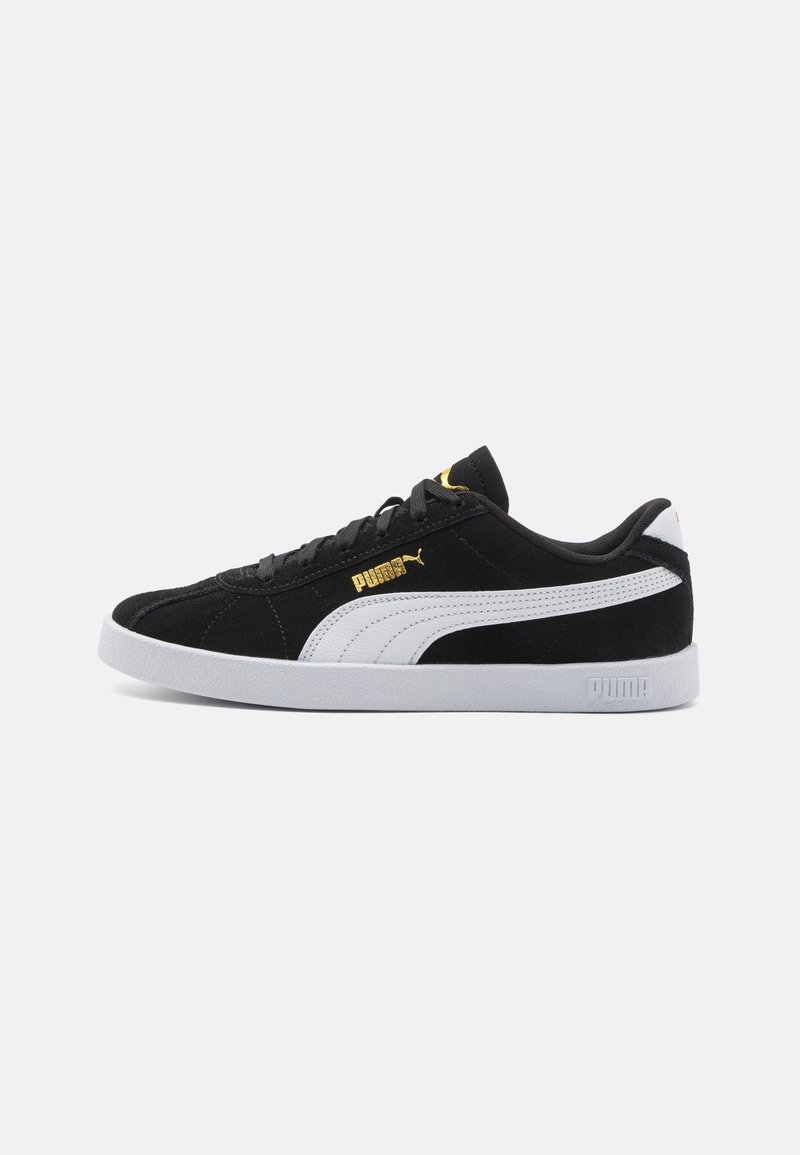 Baskets Puma noires avec bande blanche Puma sur le côté, semelle blanche, lacets noirs et logo Puma doré au-dessus de la bande.