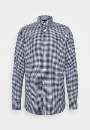 Long-sleeve button-up shirt with navy and white gingham check pattern, pointed collar, and small logo on the left chest.