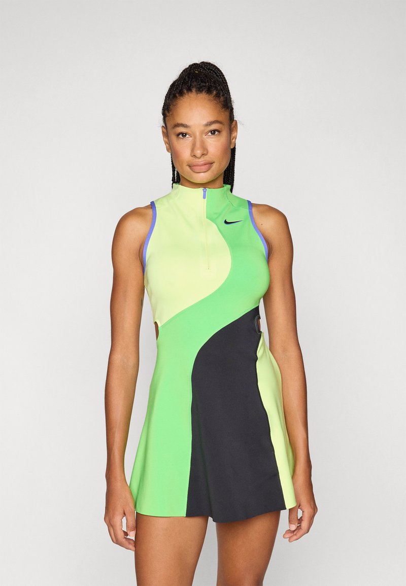 Αθλητικό φόρεμα με ψηλό γιακά και φερμουάρ, κατασκευασμένο από ύφασμα σε αποχρώσεις του πράσινου, λάιμ και μαύρου, με κοψίματα στις πλευρές και αντίθετες λεπτομέρειες.