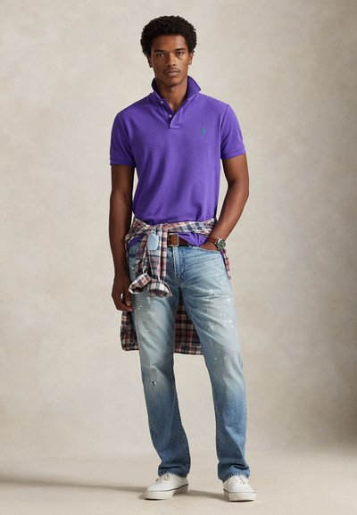 Μωβ πόλο μπλούζα με τρία κουμπιά, σε συνδυασμό με ανοιχτό μπλε τζιν με φθορές. Ένα καρό πουκάμισο δεμένο στη μέση και λευκά αθλητικά παπούτσια ολοκληρώνουν την εμφάνιση.