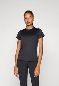 Camiseta deportiva negra de manga corta, fabricada con un tejido liso que absorbe la humedad; presenta un pequeño logotipo en el hombro izquierdo.