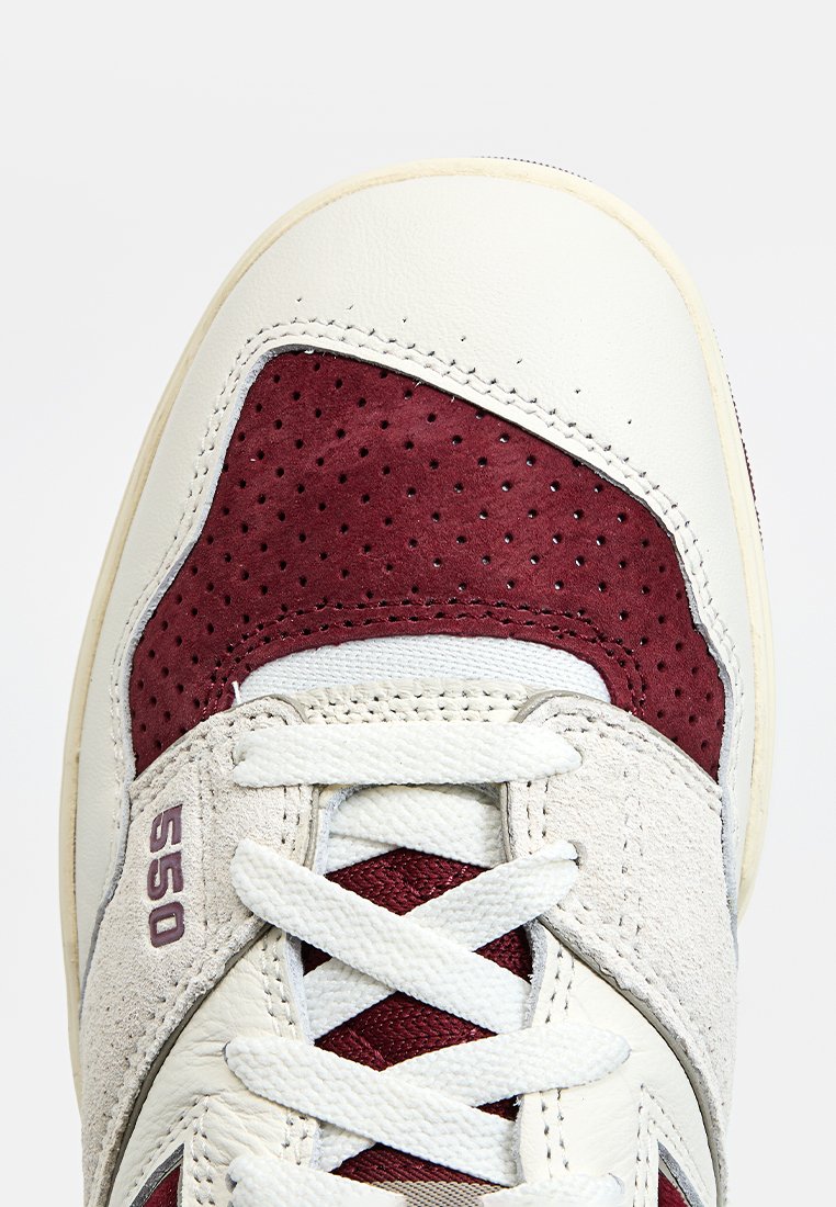 Scarpa atletica bianca e bordeaux con tomaia in pelle e camoscio, dettagli perforati bordeaux e lingua e lacci grigi texturizzati. Modello 550.
