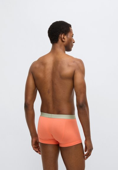 Boxers masculinos laranja com textura suave e cós elástico verde claro, apresentando um design ajustado e sem logotipos visíveis.