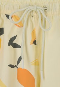 Gelbe Shorts mit einem Kordelzugbund, die ein Zitronen- und Blattmuster in Orange und Schwarz aufweisen. Hergestellt aus weichem, leichtem Material.