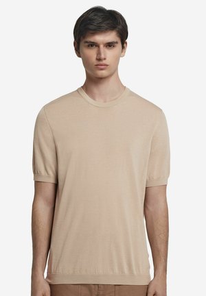 Beige kortærmet t-shirt i blødt stof med rund halsudskæring. Har en tætsiddende pasform, ribbede ærmekanter og en glat overflade.
