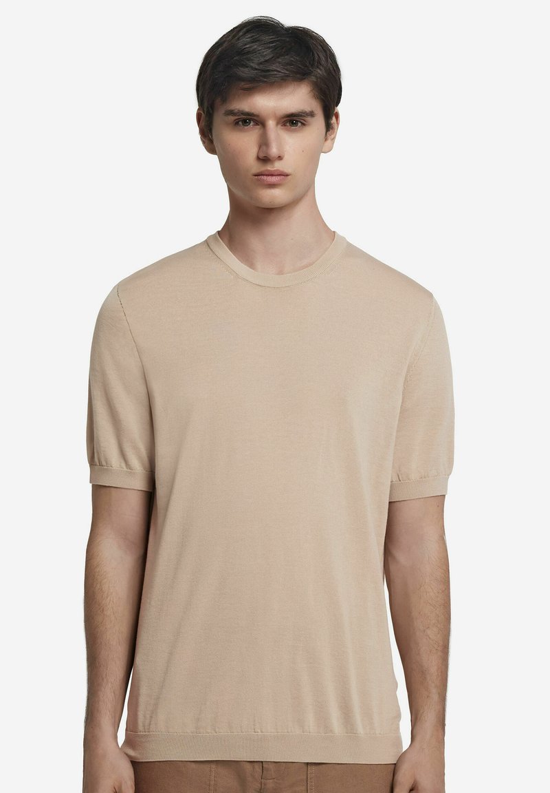 Beige kortærmet t-shirt i blødt stof med rund halsudskæring. Har en tætsiddende pasform, ribbede ærmekanter og en glat overflade.
