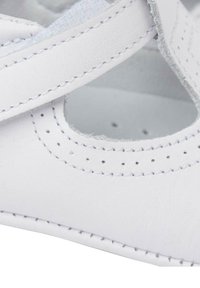 Scarpa di pelle bianca con un ritaglio rotondo, cuciture a contrasto e una morbida fodera interna. Il design presenta una fascia in Velcro per una vestibilità sicura.