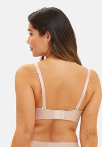 Reggiseno beige chiaro con spalline regolabili, chiusura a gancio e occhiello, tessuto liscio e design senza cuciture che mostra la vista posteriore.