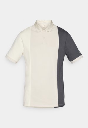 Nike polo skjorte med delt design, der har hvit på venstre side og mørkegrå på høyre side, kortermet og med klassisk krage.