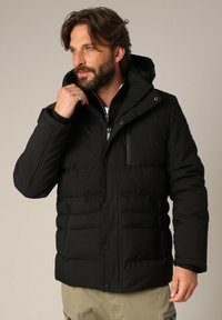 Zwarte gewatteerde jas met een rits- en knoopsluiting aan de voorkant, voorzien van een capuchon, meerdere zakken en een zachte textuur. Aangepast pasvormontwerp.
