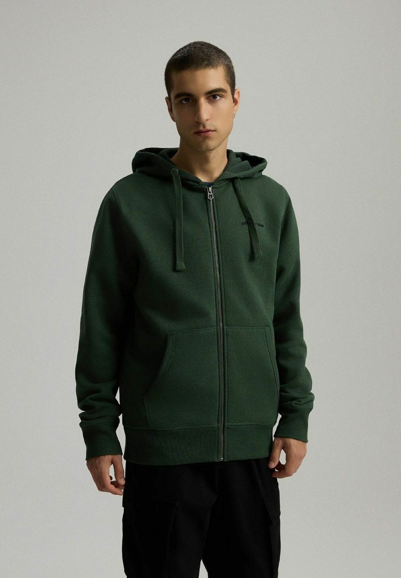 Zielona rozpinana bluza z kapturem z kieszenią kangurką, kapturem ze sznurkiem i ściagaczami przy rękawach. Miękki materiał, regularny krój, minimalne logo na piersi.