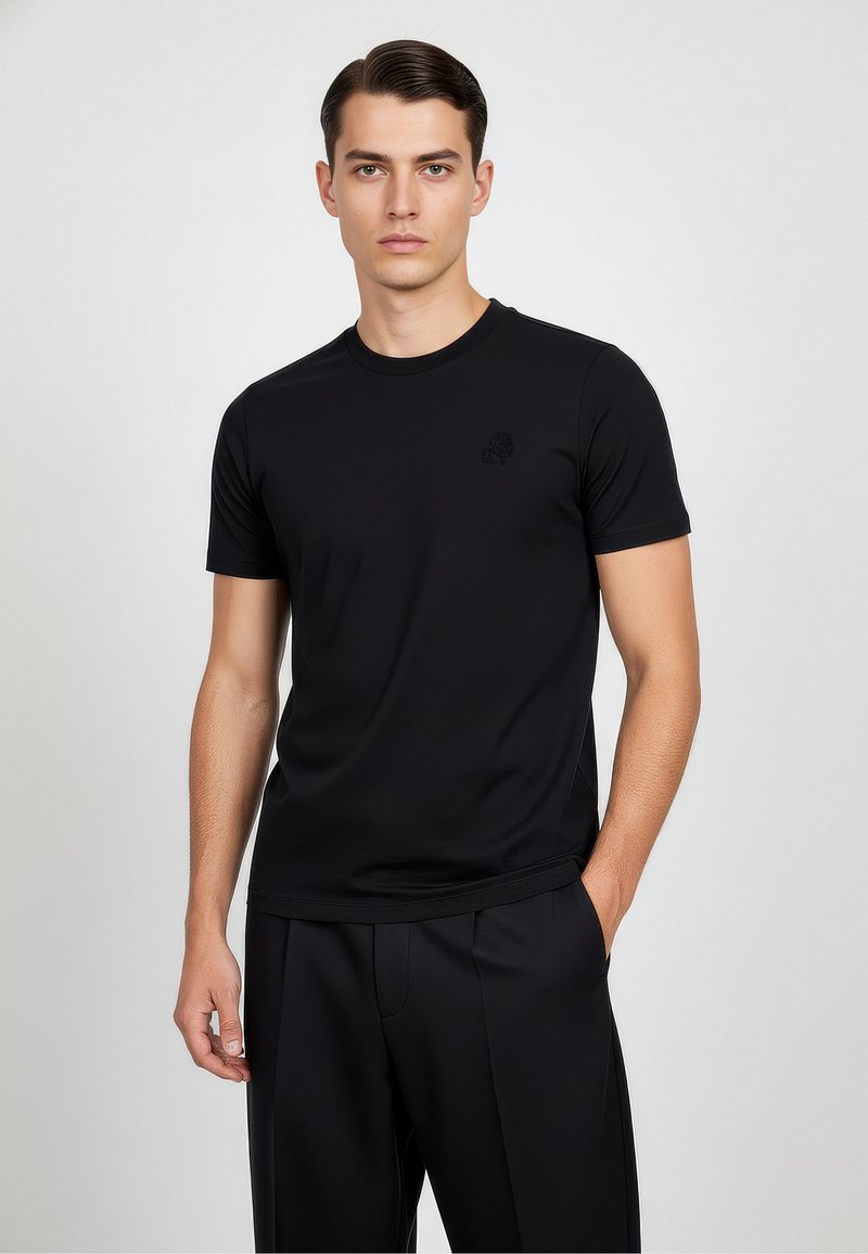 Camiseta negra de manga corta fabricada en tejido suave, con un discreto detalle de logo en el pecho y un diseño clásico de cuello redondo.