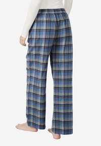 Pantalones de pijama a cuadros en azul, blanco y marrón. Ajuste suelto con cintura elástica. Tejido suave y perneras anchas para mayor comodidad.