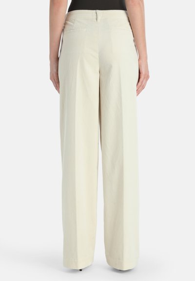 Wijduitlopende broek van lichtbeige corduroy. Heeft een gladde tailleband en twee achterzakken, met een verticale ribbelstructuur over de gehele lengte.