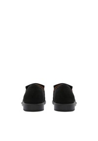 Zwarte suède instappers met een lage profiel, ronde neus en tan kleurige interieuraccenten. De platte rubberen zool biedt grip en comfort.