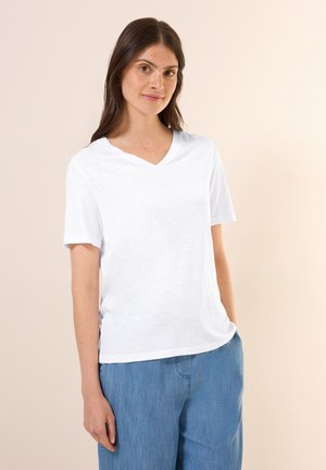 Witte katoenen T-shirt met een V-hals en korte mouwen, met een ontspannen pasvorm en een gladde textuur, gecombineerd met lichtblauwe broek.