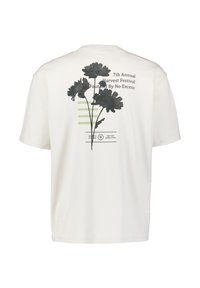Wit T-shirt met zwarte bloemmotief, groene strepen en tekst op de achterkant die luidt: "7th Annual Harvest Festival Founded By No Excess".