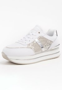 Bílé tenisky s texturovaným stříbrným hadím vzorem, kovovými doplňky a zvýšenou platformovou podrážkou. Šněrování s polstrovaným límcem.