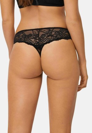 Tanga de encaje negro con patrón floral, presenta un borde festoneado y cobertura mínima, diseñado para una apariencia delicada y una sensación ligera.