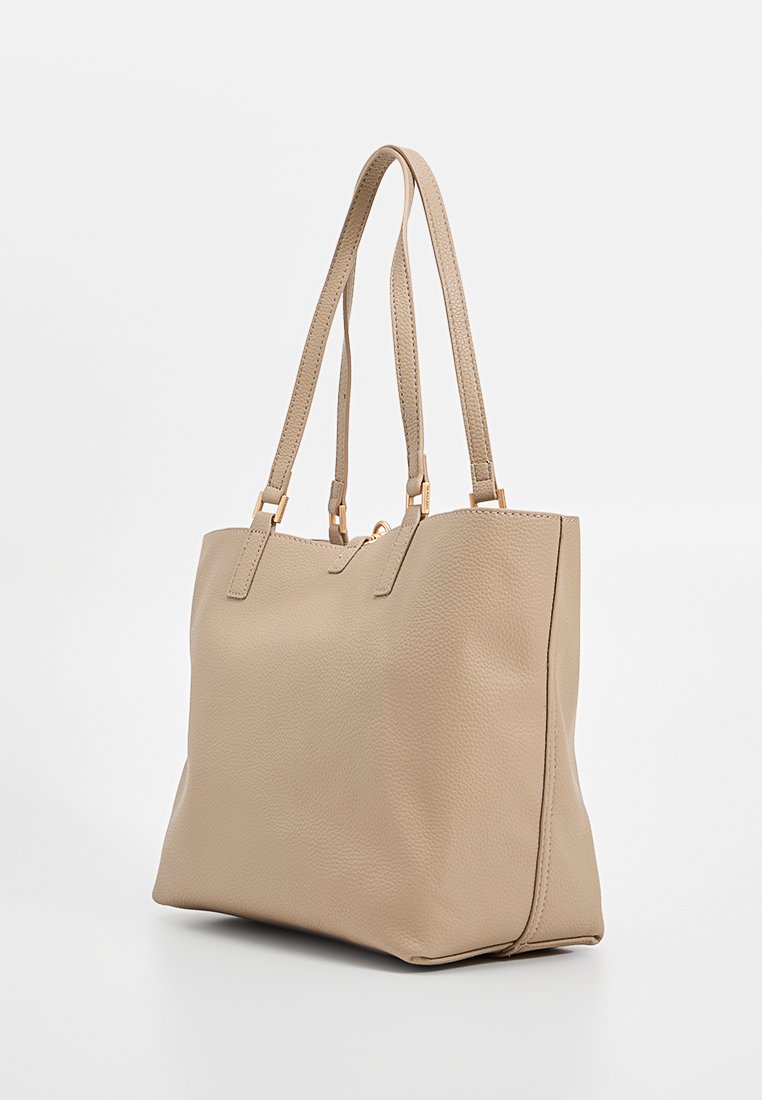 Sac fourre-tout en cuir beige avec une surface texturée, deux longues poignées et des accessoires en ton doré. Corps spacieux et design minimaliste.