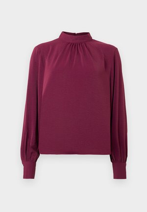 Long-sleeve, high-neck blouse in dark burgundy fabric; features gathered detailing at the neckline and fitted cuffs. Smooth texture.