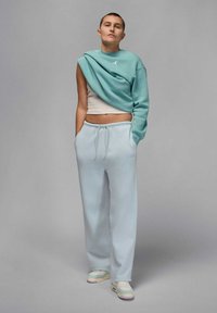 Jasnoniebieskie spodnie dresowe z elastycznym paskiem, zestawione z kremowym krótki tank topem i oversize'ową, turkusową bluzą z logo.