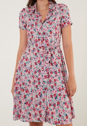 Blommig knäppklänning med krage, i en rosa bakgrund med en uppsättning röda och lila rosor, insnävda midja och korta ärmar.