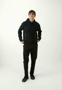 Sweatshirt à capuche noire avec une poche avant et pantalon cargo noir avec des poches latérales. Les deux articles ont une texture lisse et une coupe contemporaine.
