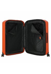 Harde oranje koffer met zwarte interieur. Voorzien van gaaszakken, ritss compartimenten en dubbele wielen voor mobiliteit. Open ontwerp.