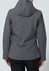 Veste en tissu gris avec capuche, présentant une surface texturée, un accent en cuir sur l'épaule, une coupe structurée et des manches longues.