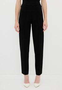 Pantalons noirs ajustés avec une taille haute, jambes légèrement fuselées et détails de couture à l'avant. Tissu lisse sans motifs visibles ni poches.