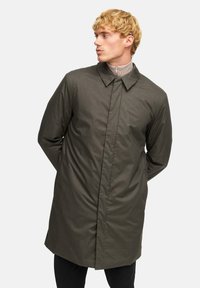 Olivgrön, lång herrkappa med rak passform, knapplöst fram och spetsig krage. Slät textur och minimalistisk design.