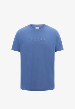 T-shirt en coton bleu à manches courtes, avec un logo "GUESS" en relief sur le devant. Encolure ronde, texture lisse, coupe décontractée.