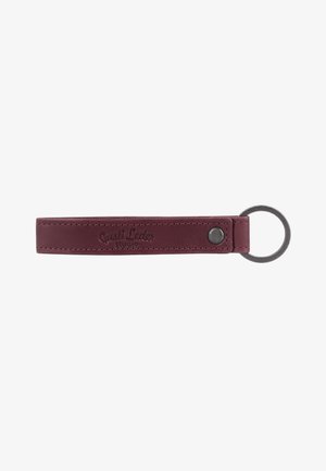 Dunkelroter Leder-Schlüsselanhänger mit Metallring und geprägt "Gusti Leder studio,", gesichert durch eine Metallniete auf weißem Hintergrund.