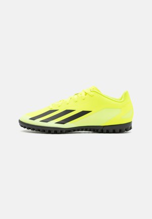 Scarpe sportive giallo neon con strisce nere, suola testurizzata per aderenza e design in rete leggera per traspirabilità.