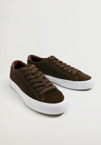 Hnědé semišové tenisky s hnědými tkaničkami, bílou gumovou podrážkou a mírně texturovaným povrchem. Jednoduchý design bez viditelného brandingu.