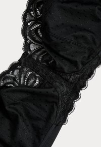 Svart lingerie med intrikata spetsdetaljer, prickig textur och vågiga kanter, med mjukt tyg för komfort och stöd.