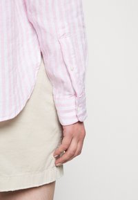 Ljusrosa och vitrandig långärmad skjorta med kn äppta manschetter, bärs över en beige kjol. Texturerat tyg med avslappnad passform.