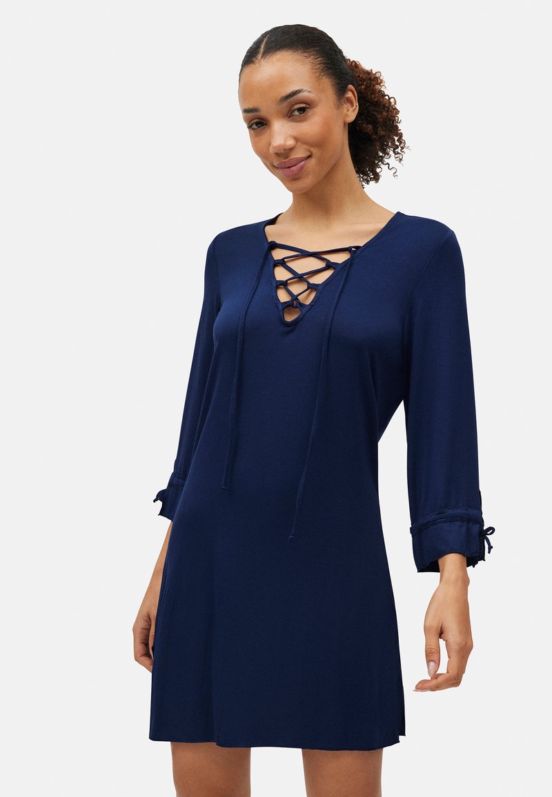 Vestido azul marino con escote con cordones, mangas de tres cuartos y detalles fruncidos en los dobladillos de las mangas. Tela suave y corte holgado.