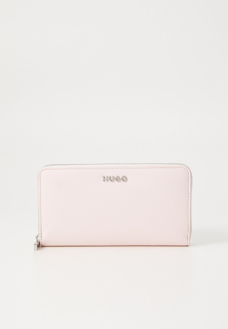 Portafoglio in pelle rosa con una texture liscia, chiusura con zip argento e logo "HUGO" in rilievo sul fronte. Forma rettangolare, design minimalista.