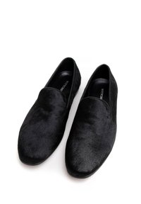 Czarne buty wsuwane wykonane z miękkiego, teksturowanego materiału z gładkim wykończeniem i zaokrąglonym noskiem. Płaskie podeszwy bez widocznych elementów metalowych.