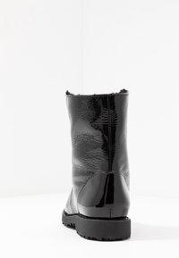Botas negras de tobillo con un exterior brillante, acabado texturizado, puntera redondeada, suela de goma y un suave borde de piel en la parte superior.
