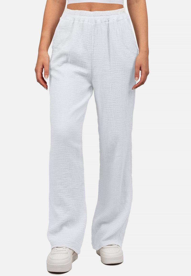 Witte, textuur rijke, brede broek met een elastische tailleband, gemaakt van zachte stof; gecombineerd met witte sneakers.