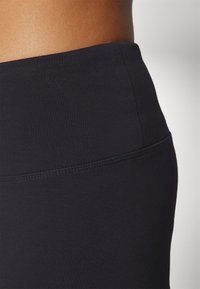 Fekete, magas derekú leggings sima, rugalmas anyagból. Egyszerű dizájn, varrott derékrésszel, látható minták vagy díszítések nélkül.