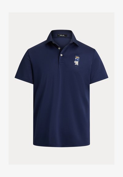 Jūras spēku polo krekls, izgatavots no gludas auduma, ar klasisku apkakli un mazu izšūtu logotipu kreisajā krūtī. Īsas piedurknes.