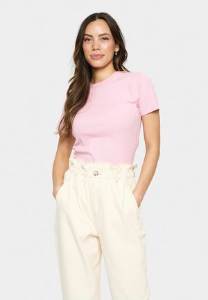 Tricou roz cu dungi, cu mâneci scurte, purtat cu pantaloni crem cu talie înaltă, având un brâu volan și detalii cu nasturi în față.
