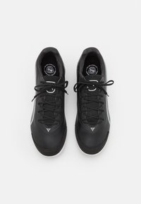 Černé sportovní tenisky s hladkým koženým svrškem, texturovanými detaily, plochými tkaničkami a bílou podrážkou. Obsahují kulaté logo na stélce.